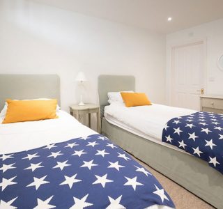 Twin Bedroom fitted with 2 single beds with stars covers, bed side table and chest of drawers